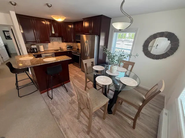 a kitchen with a refrigerator a stove a sink dishwasher with a dining table and chairs