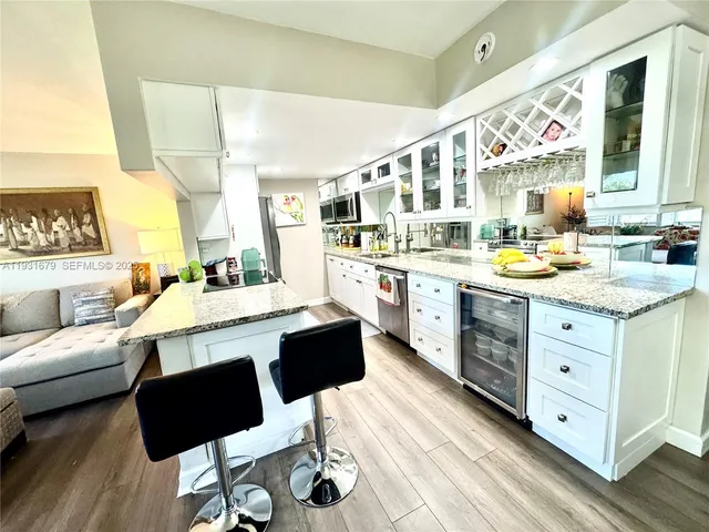 a large white kitchen with a stove a sink dishwasher and a dining table with wooden floor