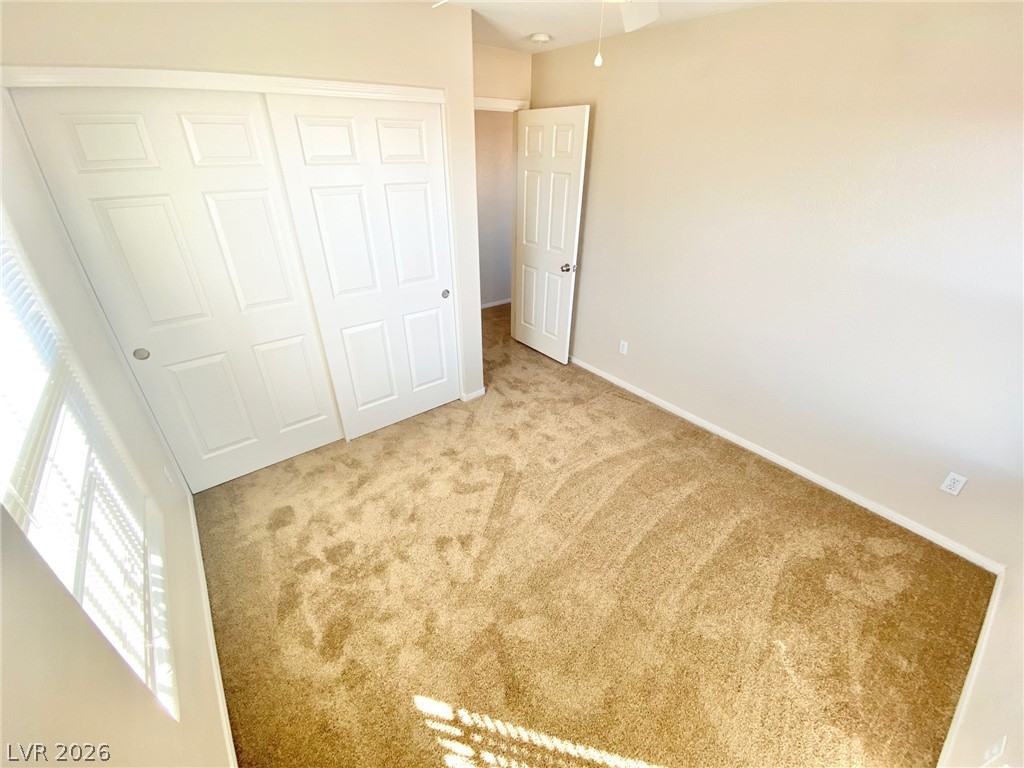 8569 Rhamus Court Las Vegas, NV 89149 - Photo 15 of 35 Sun-filled bedroom featuring soft carpeting and generous closet space with panel doors.