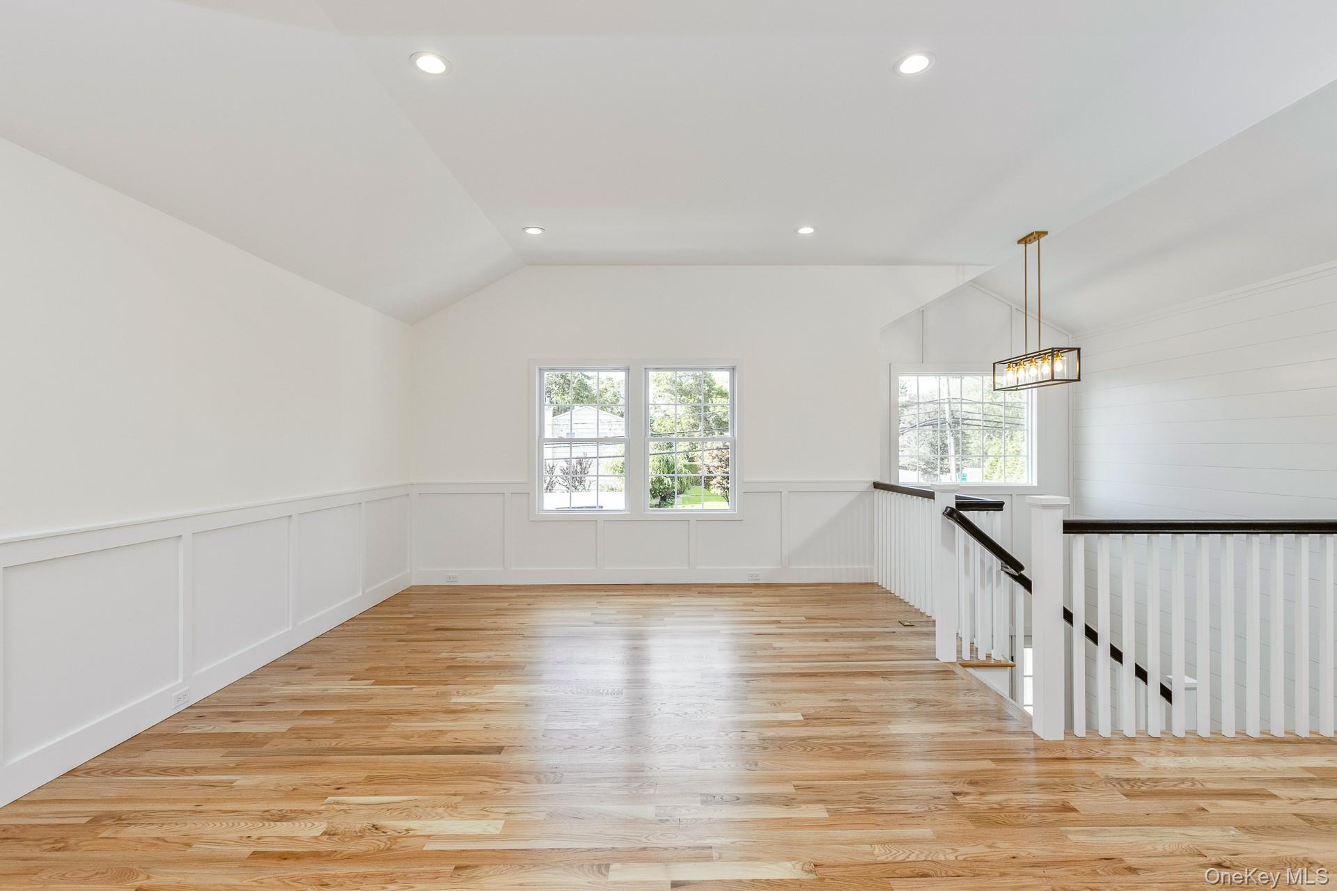 92 Park Street Blue Point, NY 11715 - Photo 17 of 32 Empty room featuring lofted ceiling, light wood-type flooring, recessed lighting, a decorative wall, and wainscoting