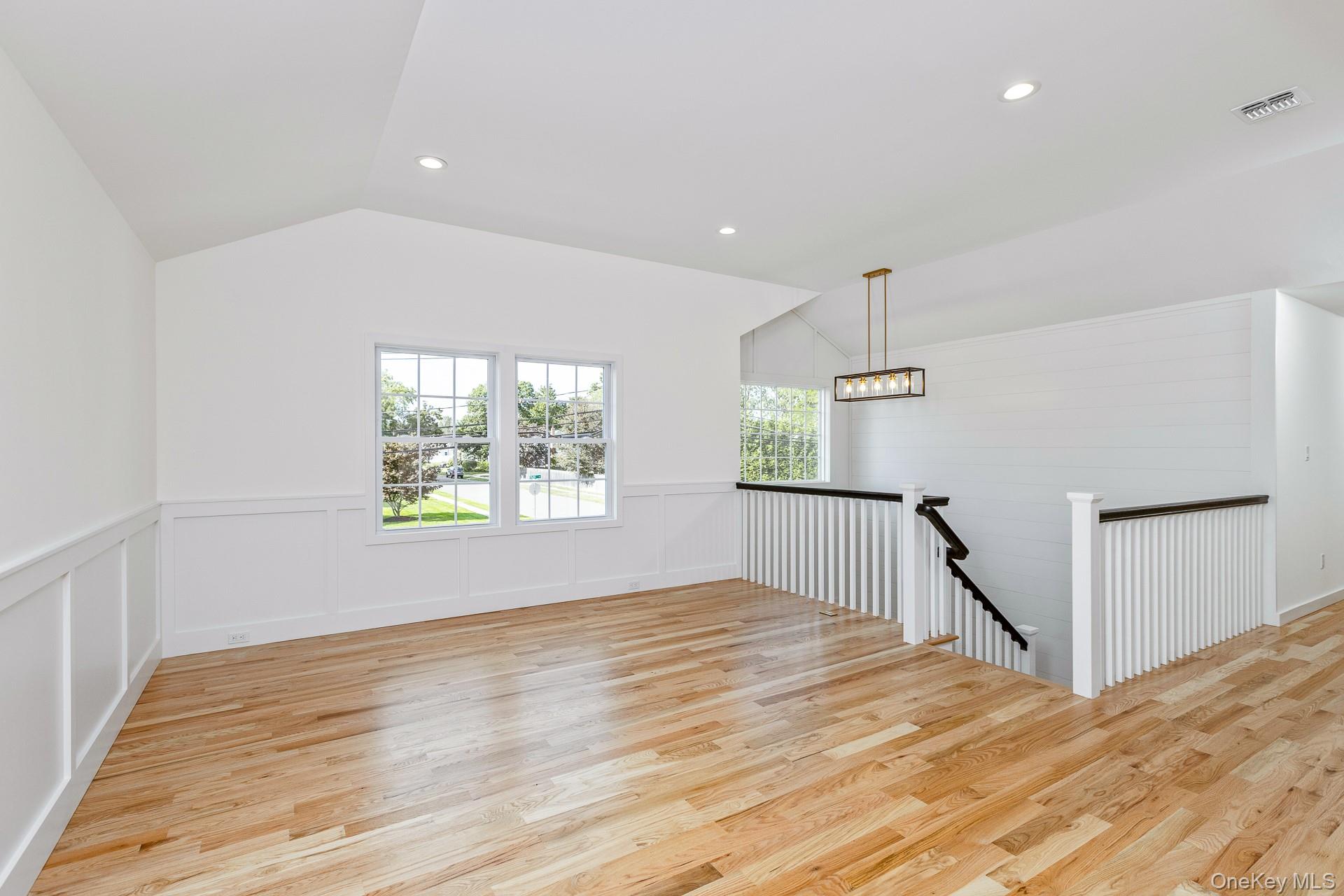 92 Park Street Blue Point, NY 11715 - Photo 18 of 32 Unfurnished room with light wood finished floors, recessed lighting, lofted ceiling, a decorative wall, and wainscoting