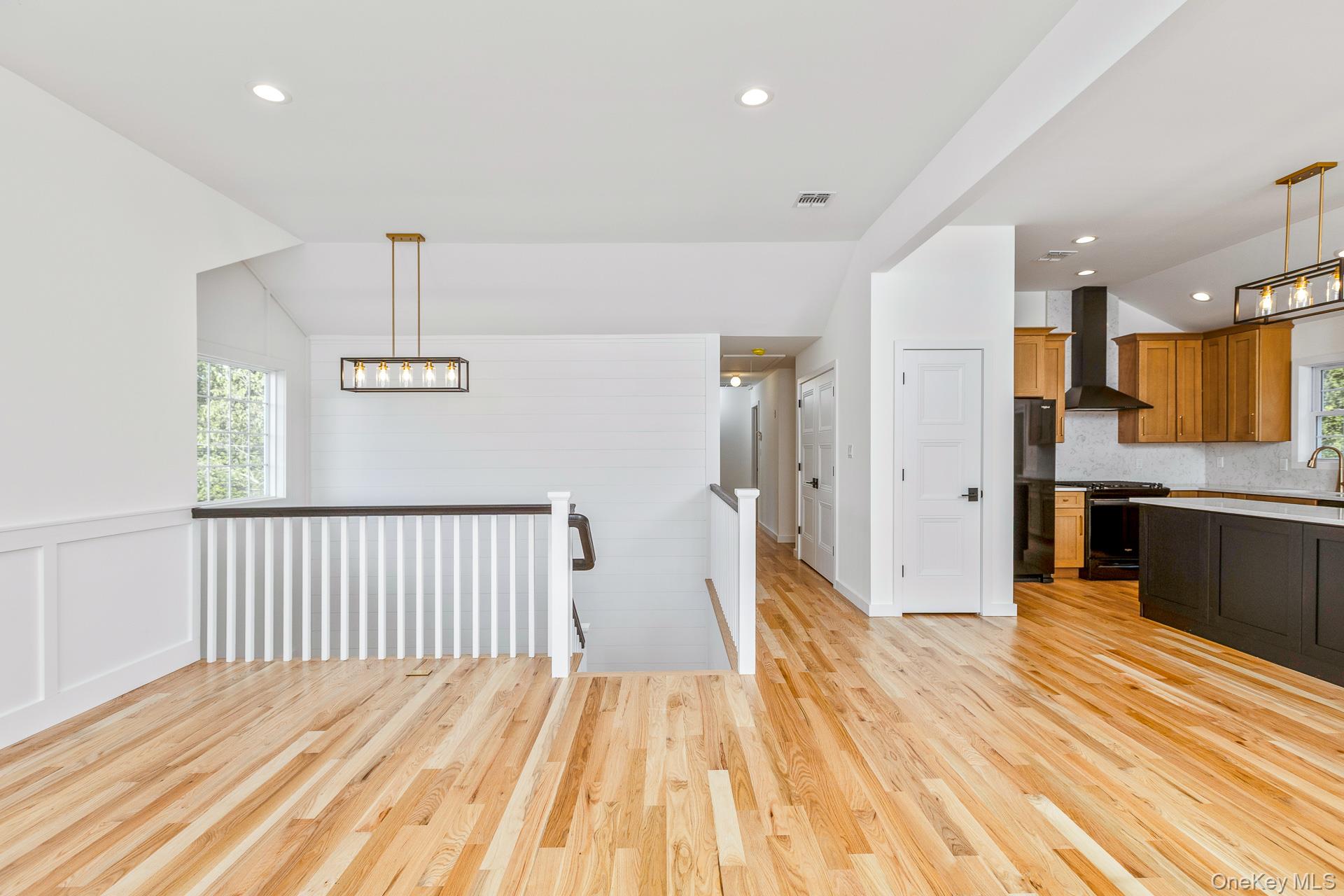 92 Park Street Blue Point, NY 11715 - Photo 19 of 32 Kitchen with hanging light fixtures, brown cabinetry, light wood-style floors, recessed lighting, and black appliances