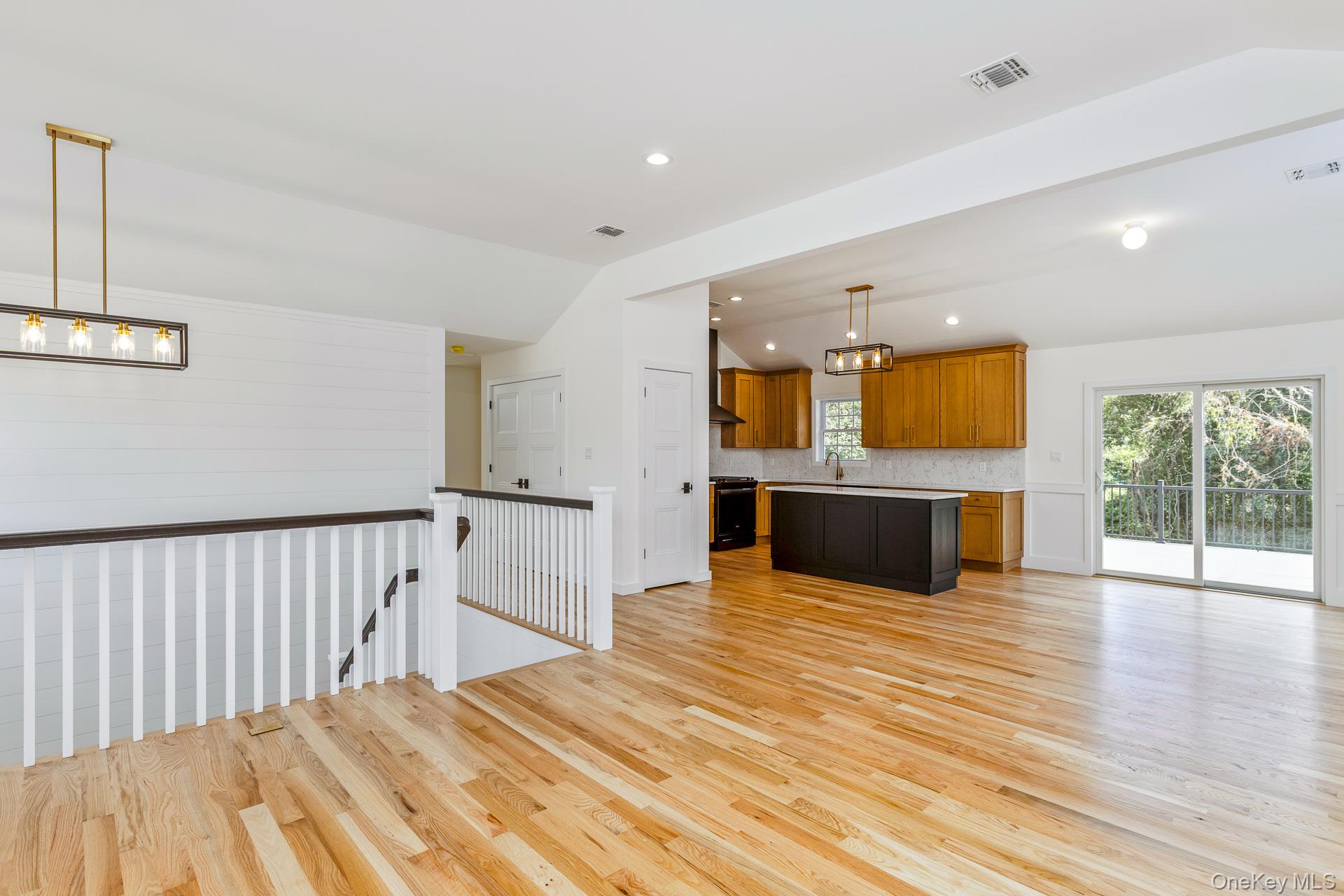 92 Park Street Blue Point, NY 11715 - Photo 30 of 32 Kitchen with hanging light fixtures, brown cabinetry, lofted ceiling, light wood finished floors, and open floor plan
