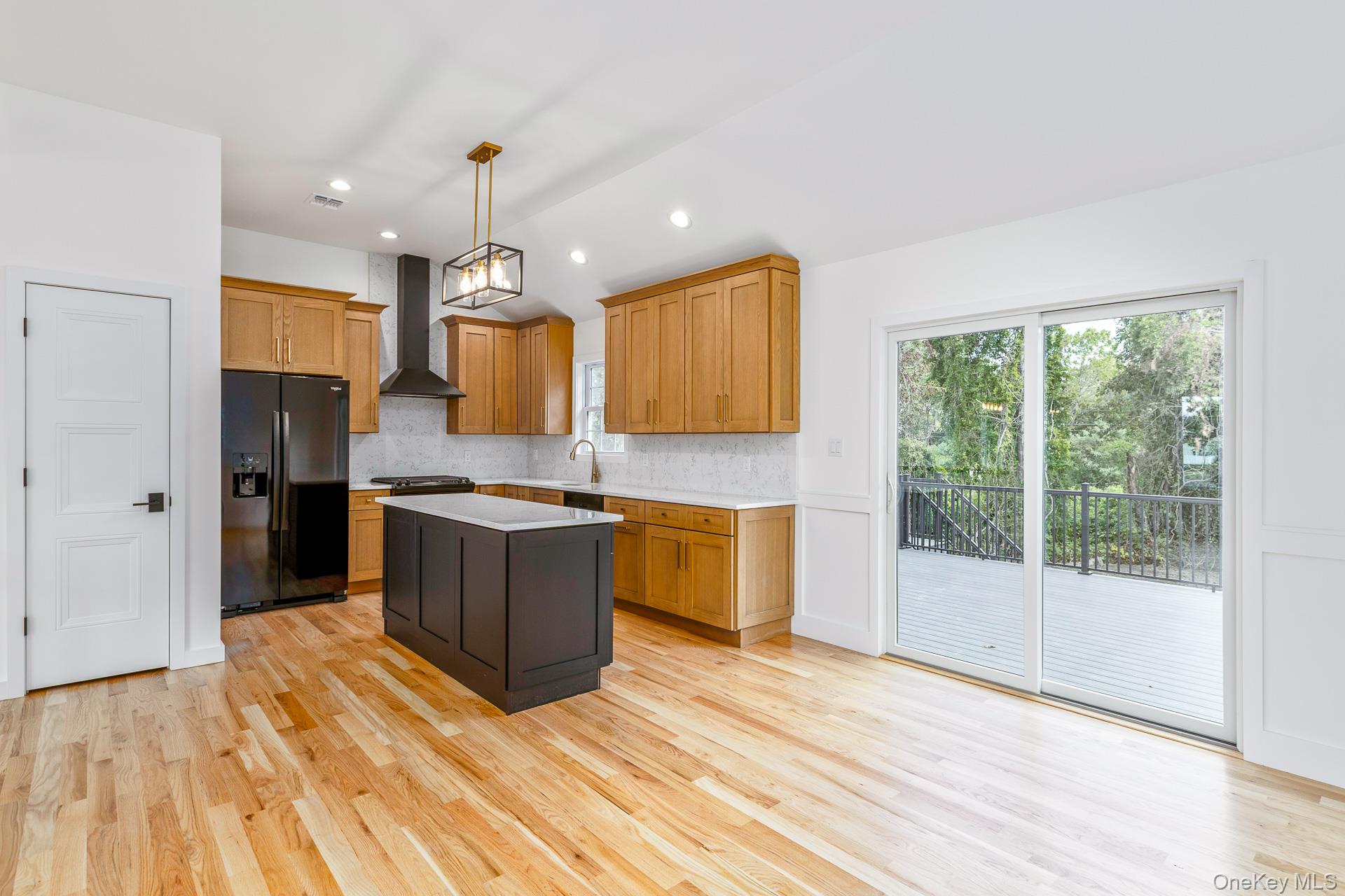 92 Park Street Blue Point, NY 11715 - Photo 21 of 32 Kitchen featuring hanging light fixtures, decorative backsplash, black fridge, a center island, and light wood-type flooring