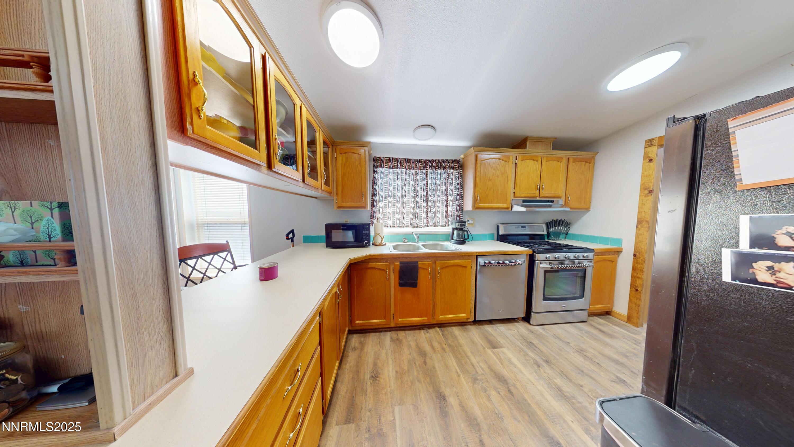 8425 Styles Court Winnemucca, NV 89445 - Photo 7 of 27 a kitchen with a refrigerator a stove top oven a sink and dishwasher with wooden floor