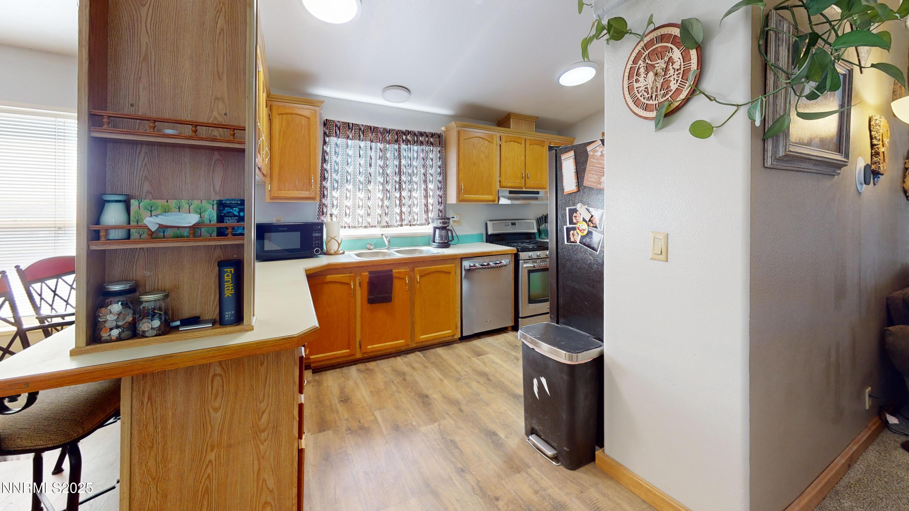 8425 Styles Court Winnemucca, NV 89445 - Photo 9 of 27 a kitchen with stainless steel appliances granite countertop a refrigerator a stove a sink dishwasher and wooden cabinets with wooden floor