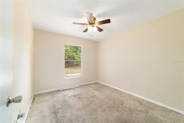 an empty room with a window and a fan