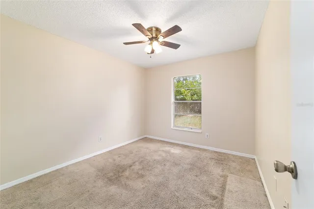 an empty room with a window and a ceiling fan