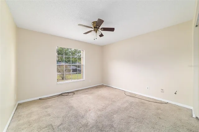an empty room with windows and ceiling fan