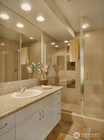 a bathroom with a granite countertop sink a mirror a bathtub and shower