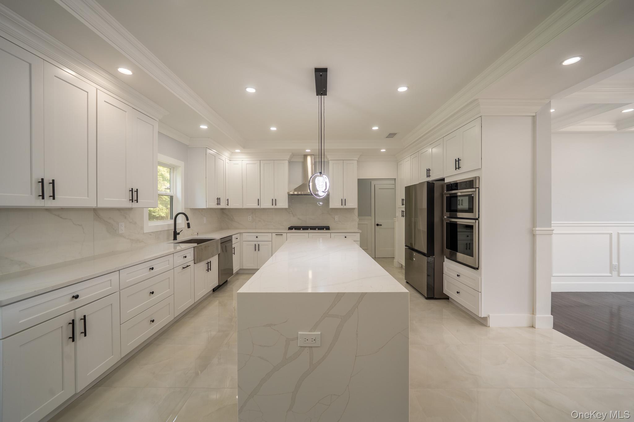 770 Cedar Street Syosset, NY 11791 - Photo 11 of 35 Kitchen featuring ornamental molding, backsplash, white cabinetry, light stone countertops, and a center island