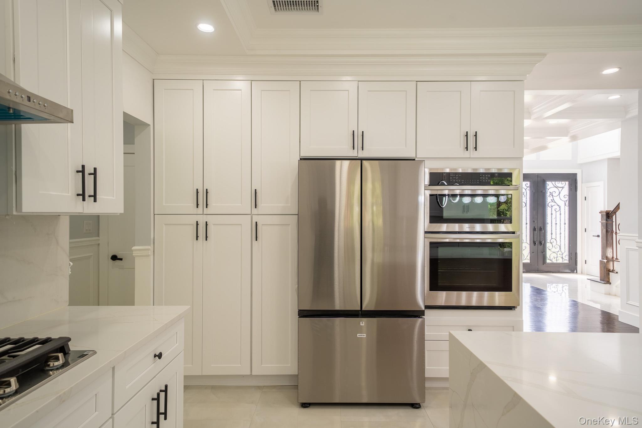 770 Cedar Street Syosset, NY 11791 - Photo 14 of 35 Kitchen with recessed lighting, stainless steel appliances, crown molding, white cabinets, and light stone counters