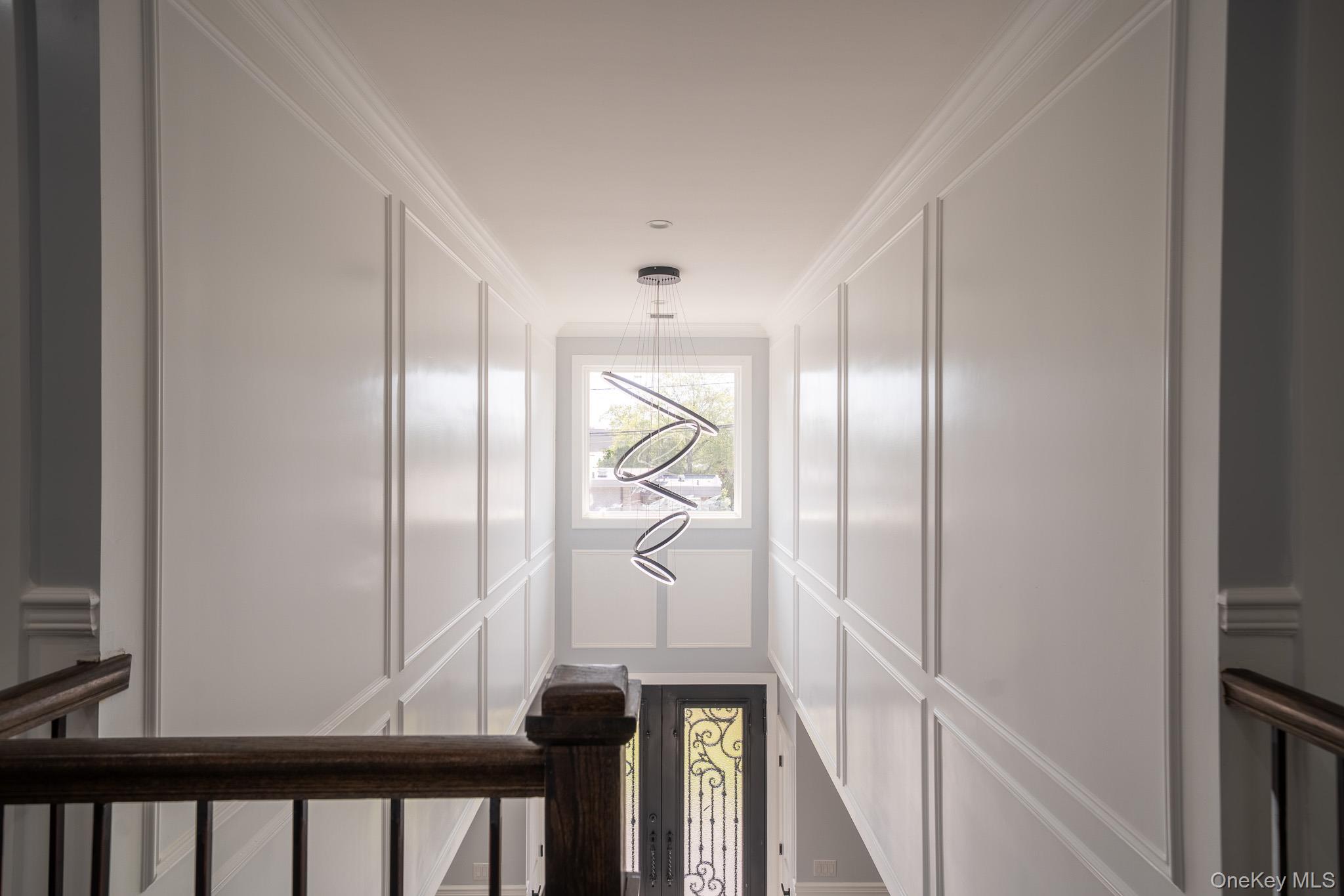 770 Cedar Street Syosset, NY 11791 - Photo 20 of 35 Hallway with crown molding, a decorative wall, and a chandelier