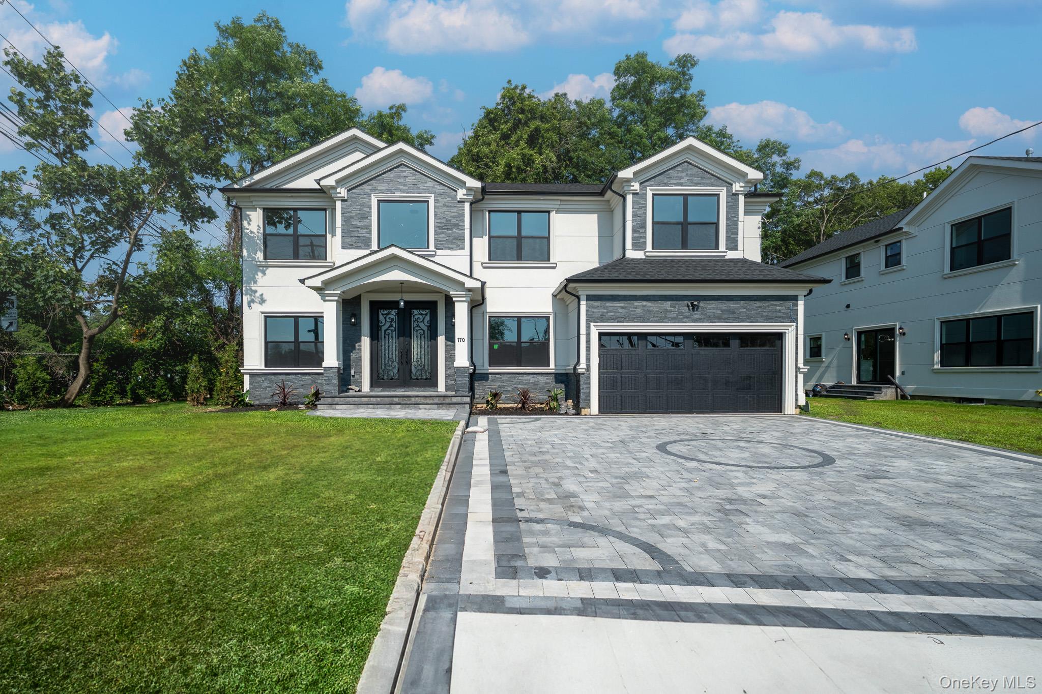 770 Cedar Street Syosset, NY 11791 - Photo 2 of 35 View of front of property featuring decorative driveway, a garage, stone siding, and a front yard