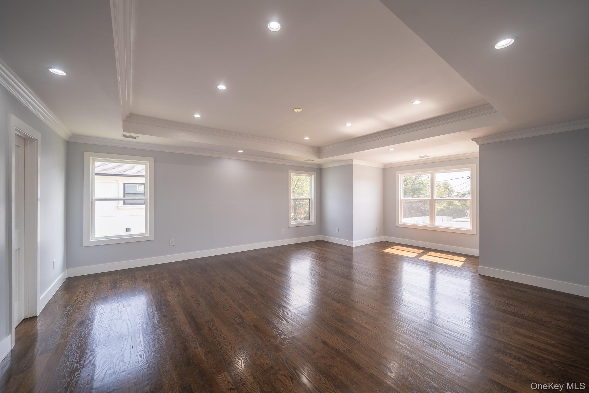 770 Cedar Street Syosset, NY 11791 - Photo 22 of 35 Empty room with ornamental molding, a tray ceiling, dark wood-style flooring, and recessed lighting