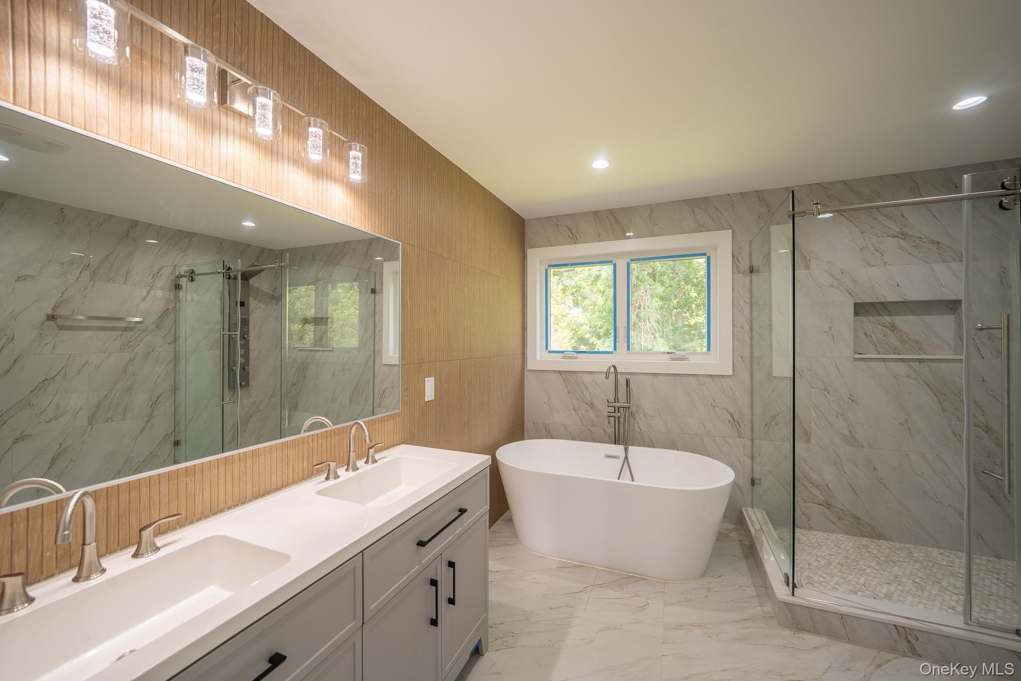 770 Cedar Street Syosset, NY 11791 - Photo 25 of 35 Full bath featuring tile walls, marble look tile flooring, a marble finish shower, a freestanding tub, and double vanity