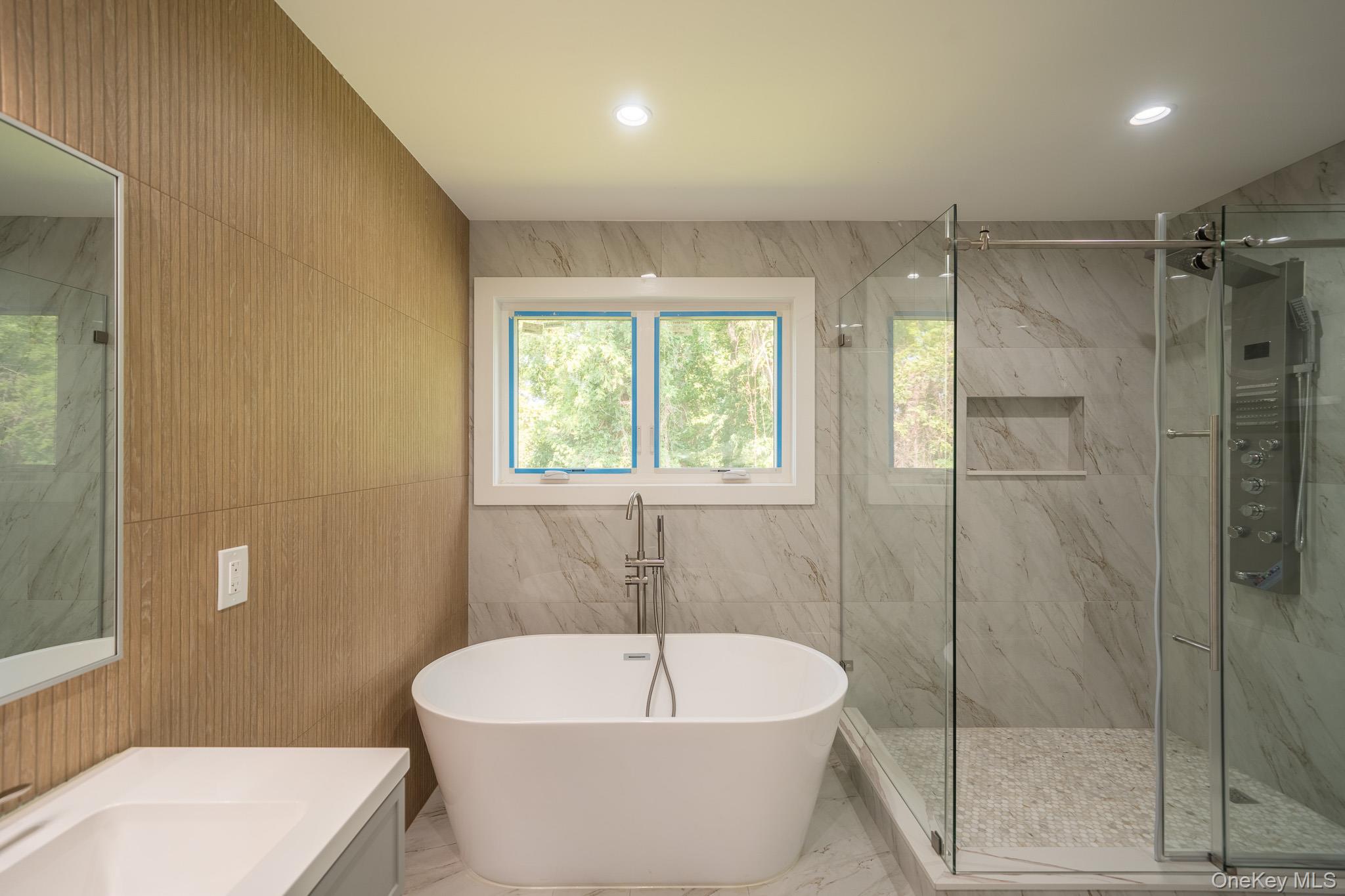 770 Cedar Street Syosset, NY 11791 - Photo 26 of 35 Bathroom with tile walls, vanity, a marble finish shower, a freestanding bath, and marble tiled flooring