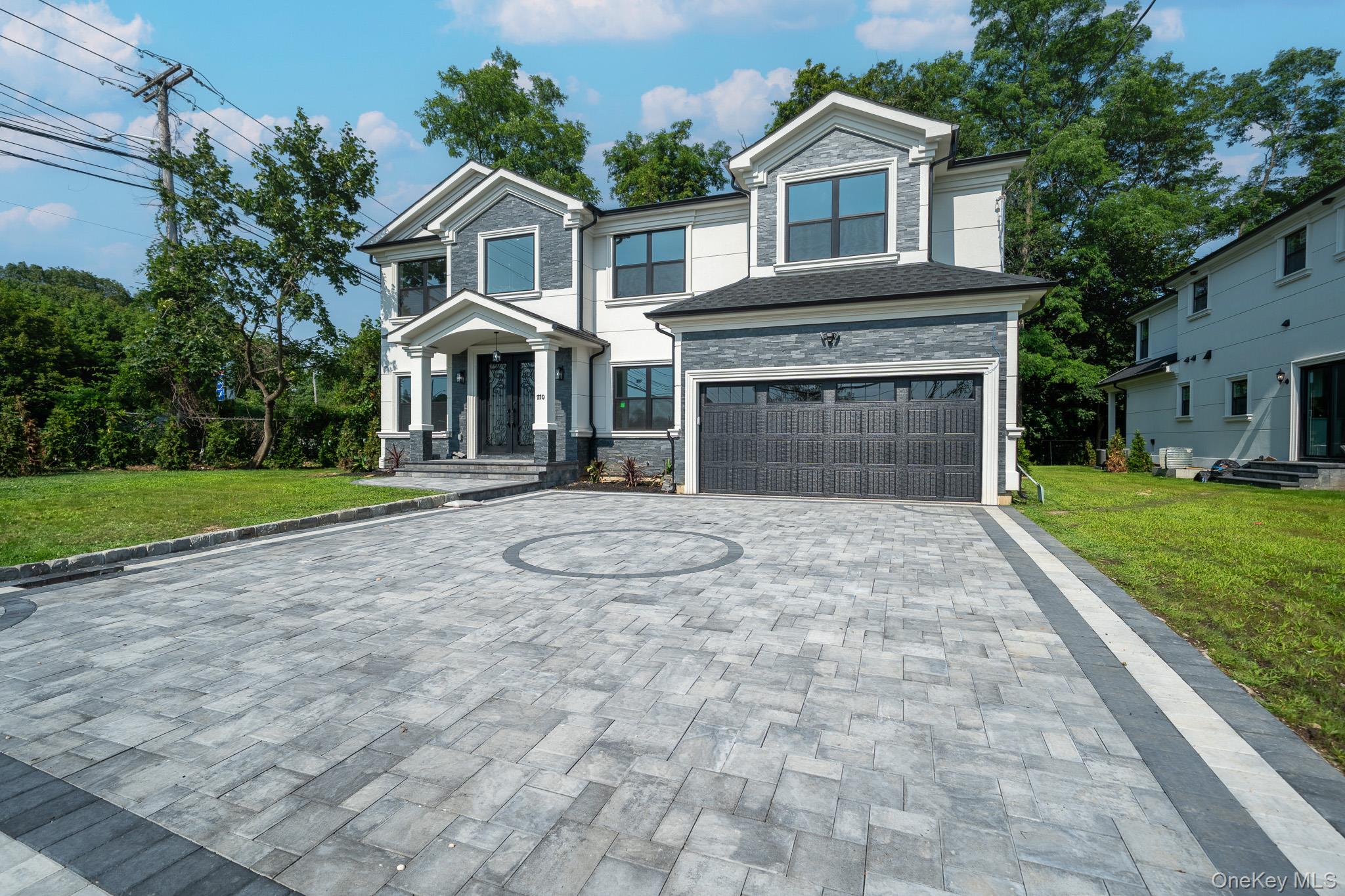 770 Cedar Street Syosset, NY 11791 - Photo 3 of 35 View of front facade with decorative driveway, a garage, a front yard, and stone siding