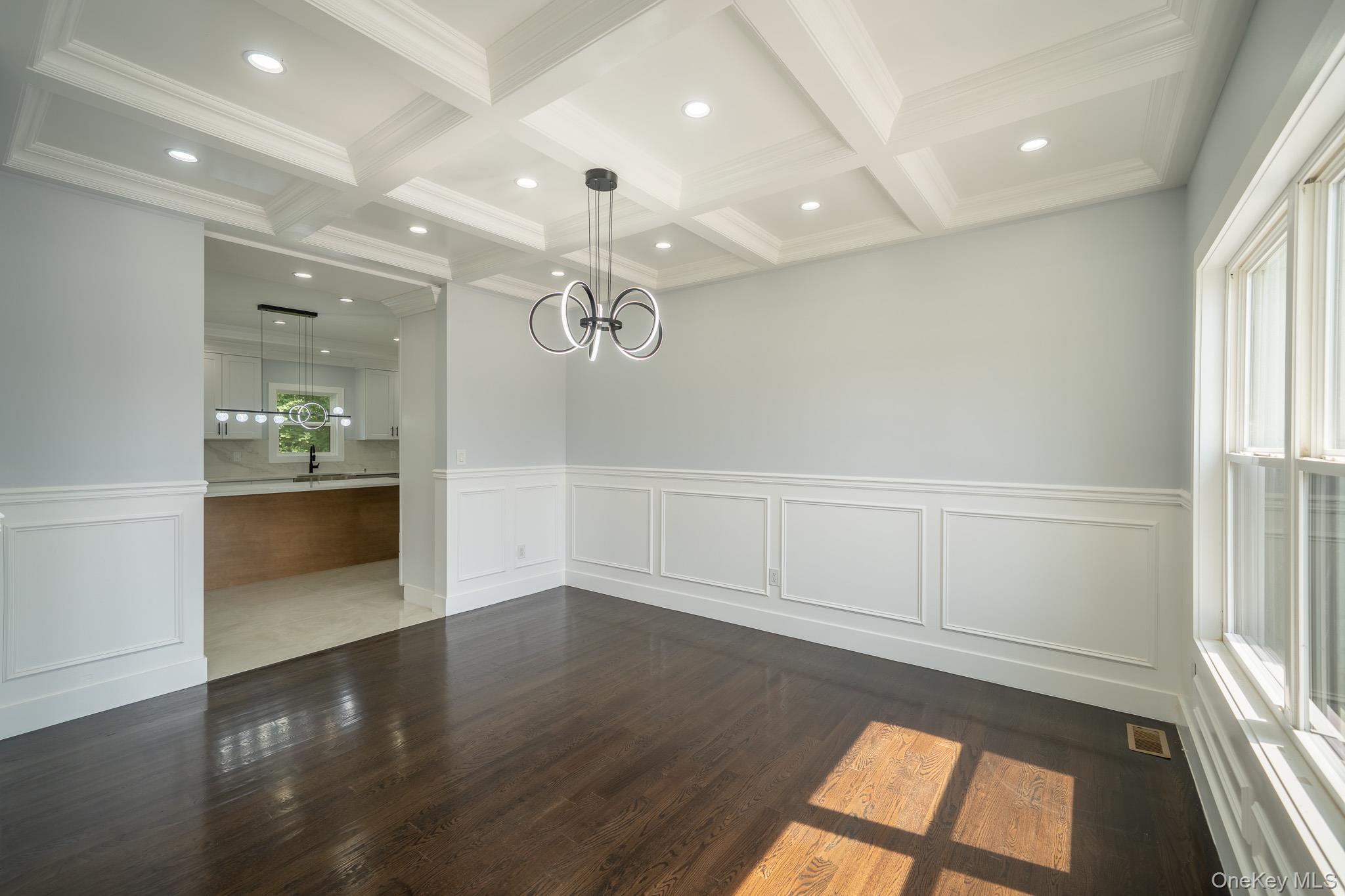 770 Cedar Street Syosset, NY 11791 - Photo 5 of 35 Unfurnished dining area with a decorative wall, a wainscoted wall, dark wood finished floors, and a chandelier