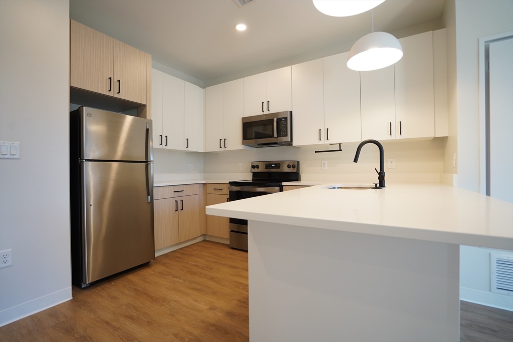 289 Walk Hill Street, Unit 327 Boston, MA 02131 - Photo 24 of 31 a kitchen with a refrigerator a stove a sink and a microwave