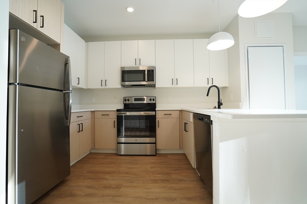289 Walk Hill Street, Unit 327 Boston, MA 02131 - Photo 25 of 31 a kitchen with white cabinets and stainless steel appliances