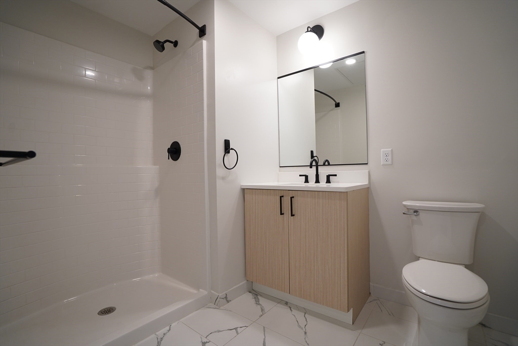 289 Walk Hill Street, Unit 327 Boston, MA 02131 - Photo 30 of 31 a bathroom with a shower a toilet and a sink