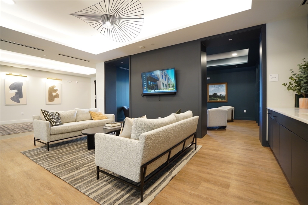 289 Walk Hill Street, Unit 327 Boston, MA 02131 - Photo 5 of 31 a living room with furniture and a chandelier