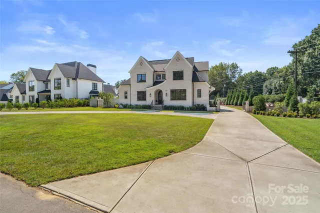 a view of a white house next to a yard with big trees
