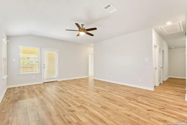a view of empty room with wooden floor and fan