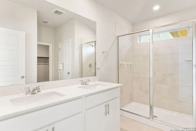 a bathroom with a double vanity sink mirror and shower