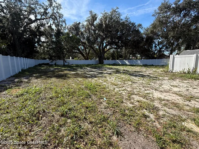 a view of a yard with wooden fence