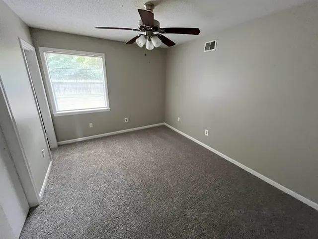 an empty room with a window and a fan