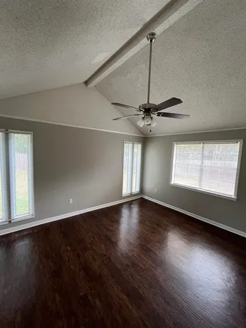an empty room with wooden floor chandelier fan and windows