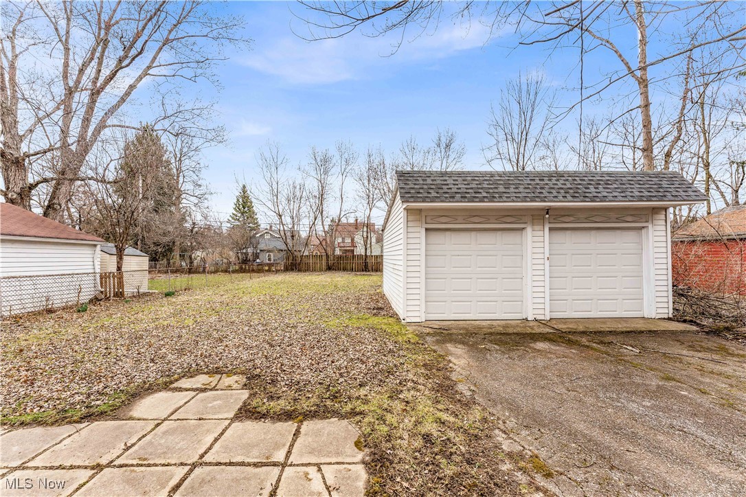 View of yard with fence, an outbuilding, and a garage