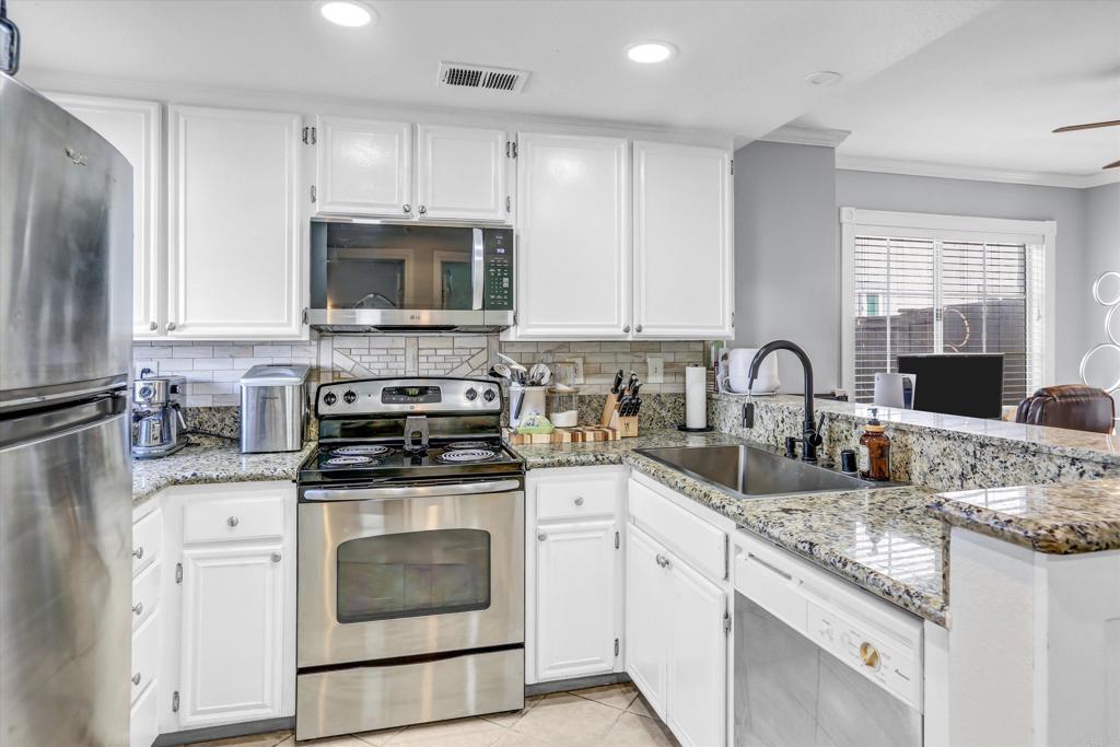 2102 Kings View Circle Spring Valley, CA 91977 - Photo 8 of 27 a kitchen with granite countertop a stove sink and cabinets