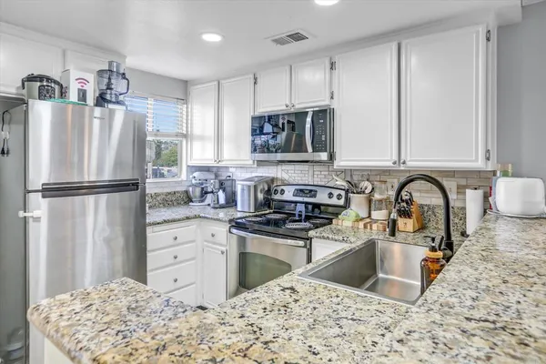 a kitchen with stainless steel appliances granite countertop a refrigerator sink and stove