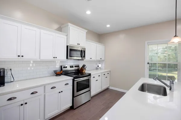 a kitchen with granite countertop white cabinets sink and stainless steel appliances