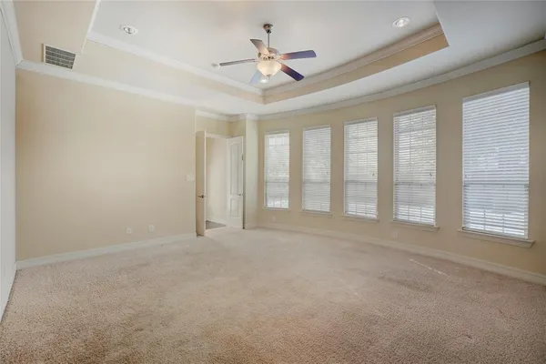 an empty room with chandelier fan and windows