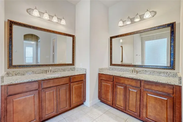 a bathroom with a granite countertop double vanity sink and a mirror