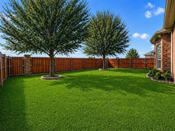 a view of backyard with table and chairs and wooden fence