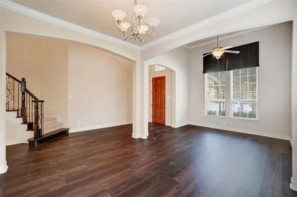 a view of an empty room with wooden floor ceiling fan and a window