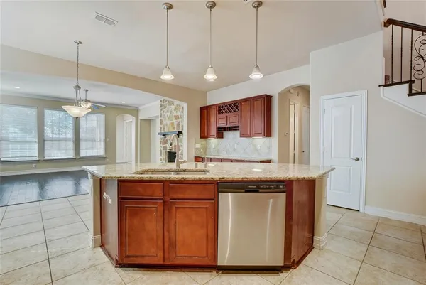 a kitchen with stainless steel appliances granite countertop a sink a stove and a wooden floor