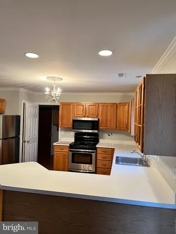 a large kitchen with stainless steel appliances a refrigerator a stove and a sink with wooden cabinets