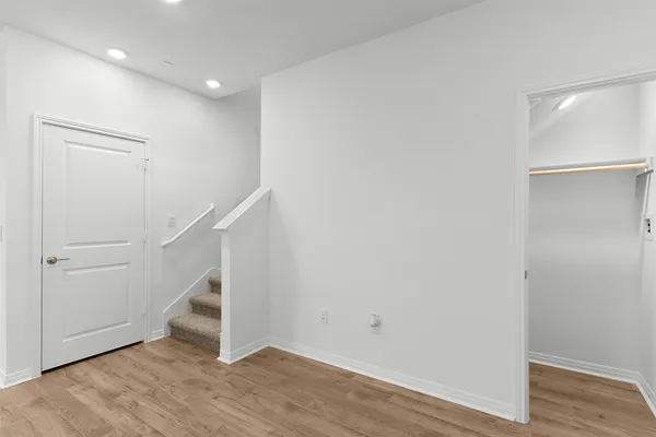 a view of an empty room with kitchen and window