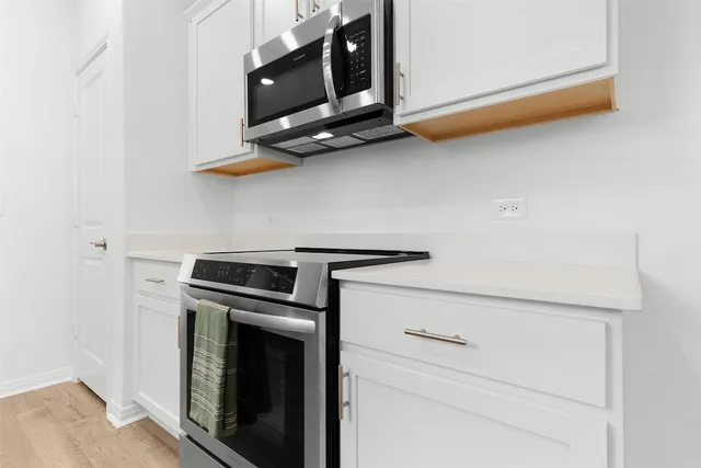 a kitchen with white cabinets and refrigerator
