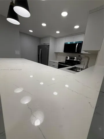 a large white kitchen with a refrigerator a stove and a sink