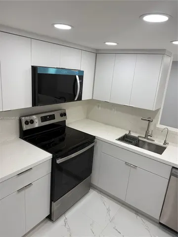 a large kitchen with stainless steel appliances a large counter top