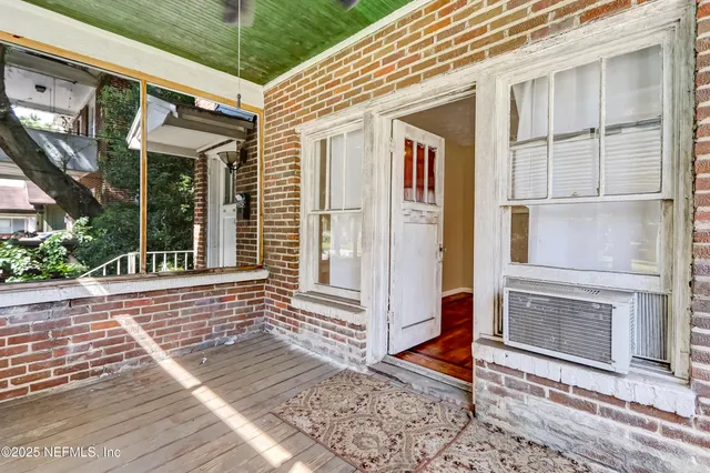 a view of an empty room with wooden floor and a fireplace