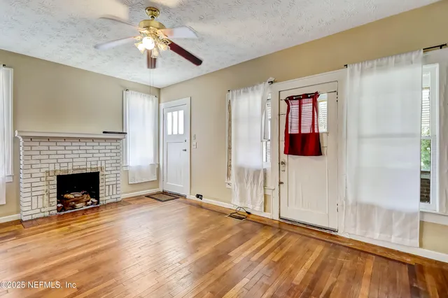 a view of an empty room with window and wooden floor