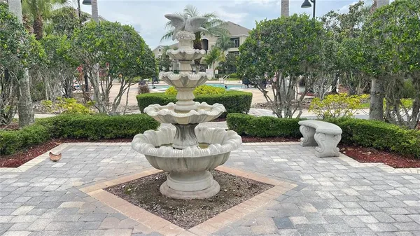 a view of a fountain in the yard with potted plants and trees